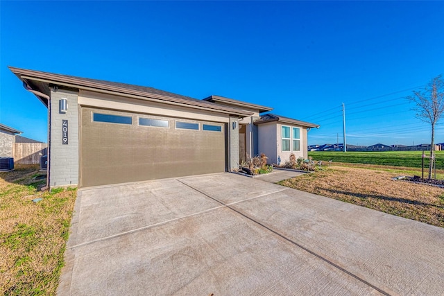 prairie-style house with brick siding, an attached garage, concrete driveway, and central AC