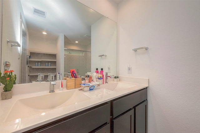 bathroom with a sink, visible vents, a stall shower, and double vanity