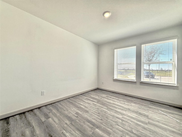 unfurnished room with baseboards and wood finished floors