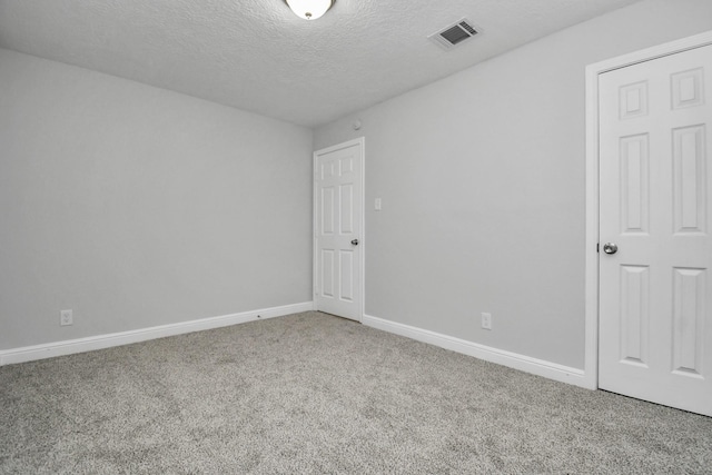 spare room featuring carpet and a textured ceiling