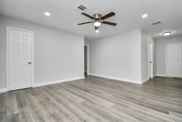 spare room with ceiling fan, a textured ceiling, and light wood-type flooring