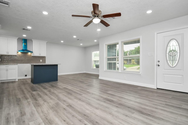 unfurnished living room with ceiling fan, a textured ceiling, and light wood-type flooring