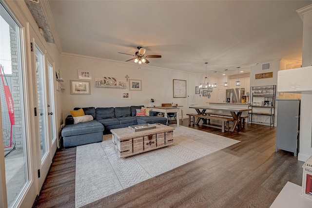 living room with ceiling fan with notable chandelier, wood-type flooring, and crown molding