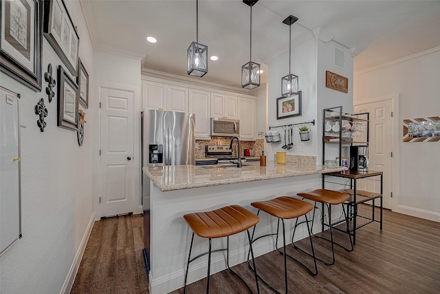 kitchen with light stone countertops, ornamental molding, stainless steel appliances, decorative light fixtures, and white cabinets