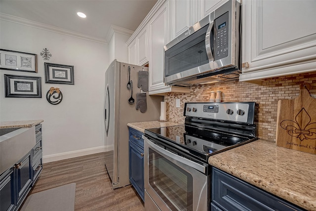 kitchen featuring white cabinets, blue cabinetry, stainless steel appliances, and ornamental molding