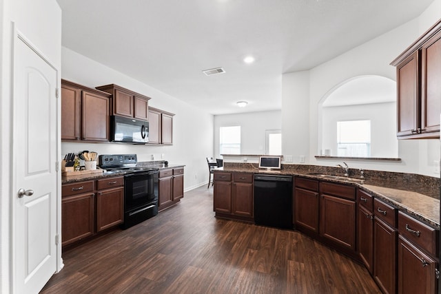 kitchen with black appliances, sink, dark stone countertops, dark hardwood / wood-style flooring, and kitchen peninsula