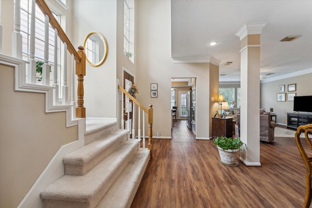 foyer entrance with decorative columns, dark hardwood / wood-style flooring, and ornamental molding