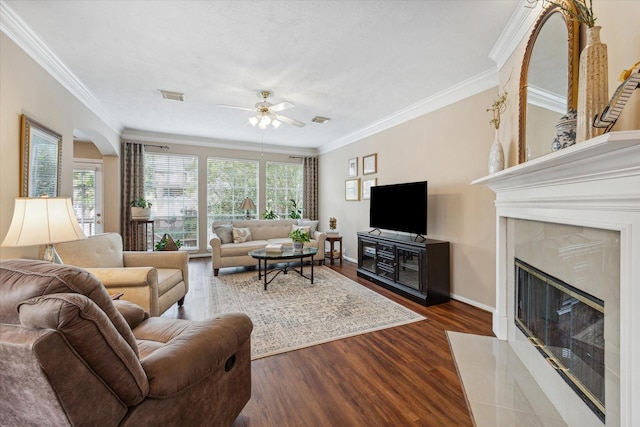 living room featuring dark hardwood / wood-style floors, ceiling fan, ornamental molding, and a fireplace