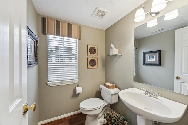 bathroom featuring a textured ceiling, sink, hardwood / wood-style flooring, a chandelier, and toilet