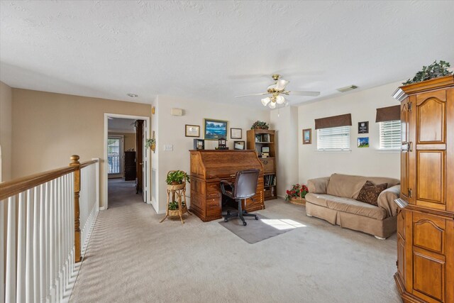 office space with light carpet, a textured ceiling, and ceiling fan