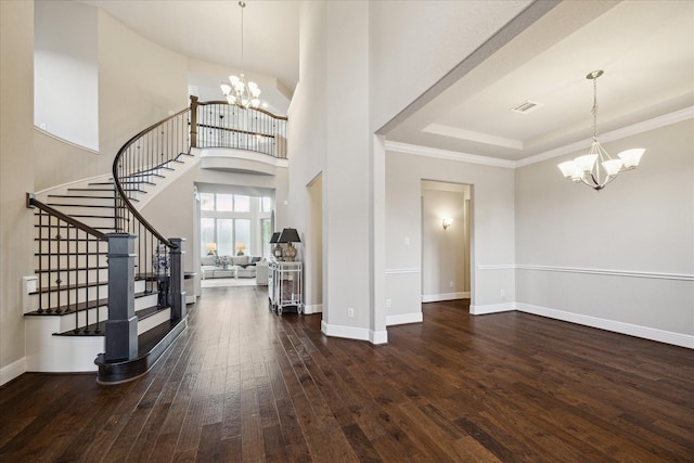 entryway featuring dark wood-type flooring, a chandelier, a high ceiling, and ornamental molding