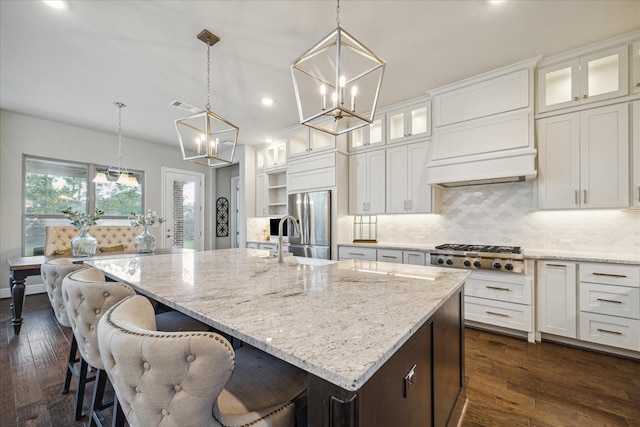 kitchen with stainless steel appliances, white cabinetry, hanging light fixtures, and a large island