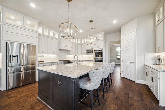 kitchen featuring sink, hanging light fixtures, stainless steel appliances, a kitchen island with sink, and white cabinets