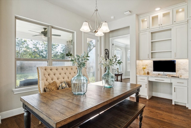 dining area with ceiling fan with notable chandelier, built in desk, and dark hardwood / wood-style floors