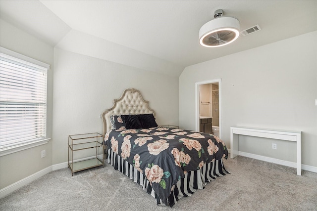 carpeted bedroom featuring vaulted ceiling and ensuite bath