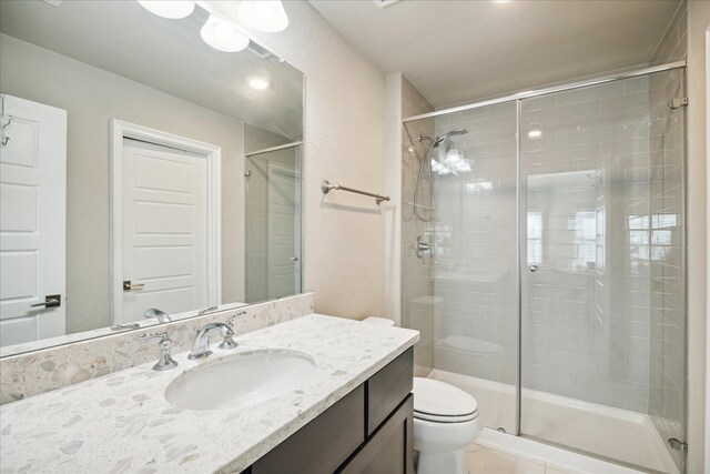 bathroom with tile patterned floors, toilet, an enclosed shower, and vanity