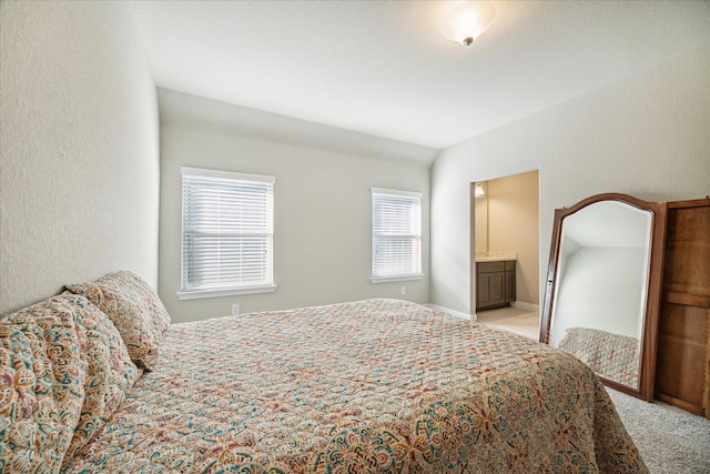 bedroom with light carpet, connected bathroom, and multiple windows