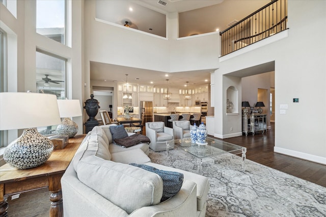 living room with a towering ceiling, ceiling fan, and dark wood-type flooring