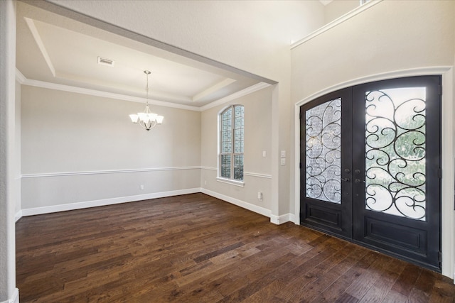 foyer featuring dark hardwood / wood-style flooring, an inviting chandelier, a raised ceiling, and french doors