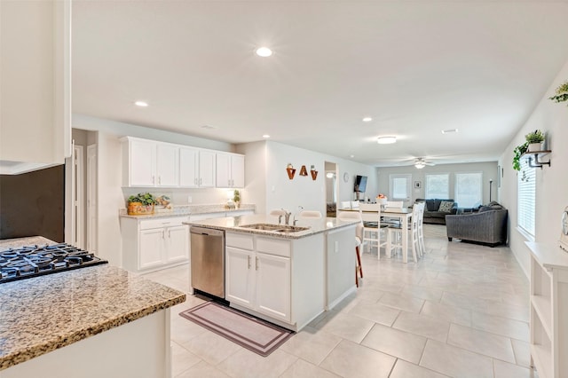 kitchen featuring sink, stainless steel appliances, light stone counters, a center island with sink, and white cabinets