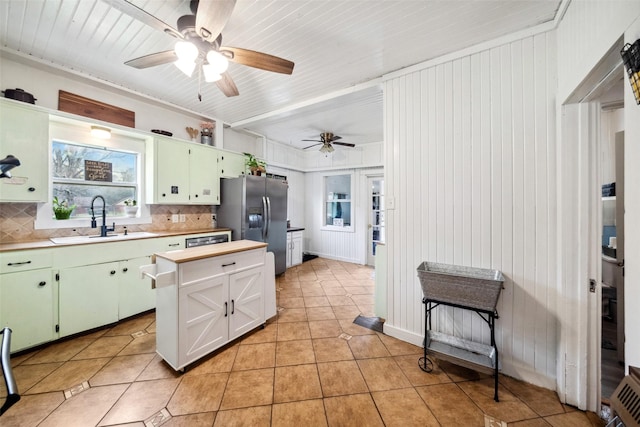 kitchen with stainless steel fridge with ice dispenser, backsplash, light tile patterned floors, and sink