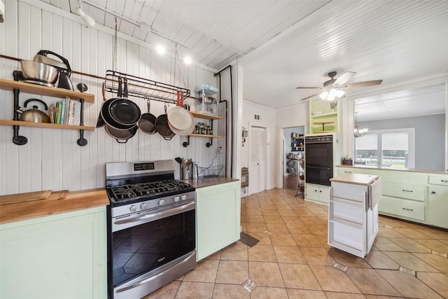 kitchen featuring ceiling fan with notable chandelier, green cabinetry, light tile patterned floors, double oven, and gas stove