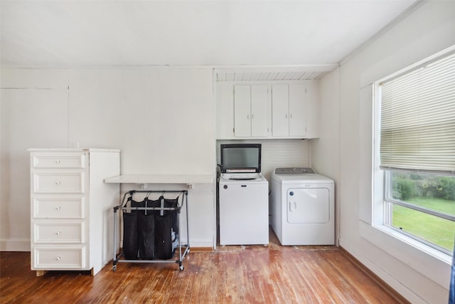 laundry room featuring cabinets, washing machine and dryer, and hardwood / wood-style flooring