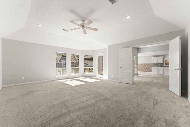 unfurnished living room featuring a tray ceiling, ceiling fan, light colored carpet, and lofted ceiling