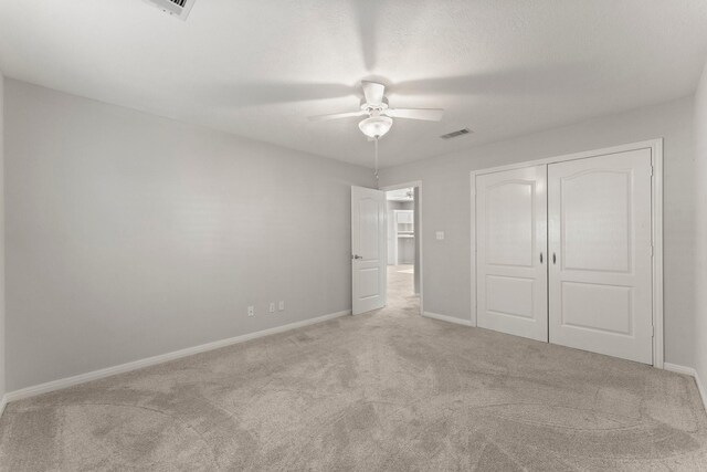 unfurnished bedroom with ceiling fan, a closet, and light carpet