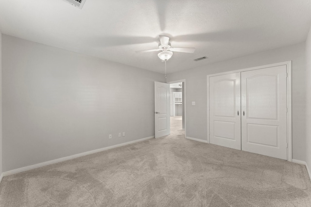 unfurnished bedroom featuring light carpet, a ceiling fan, visible vents, baseboards, and a closet