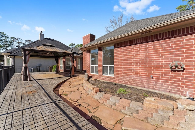 rear view of house featuring a patio area, brick siding, fence, and a gazebo