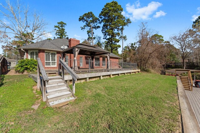 back of property featuring a lawn, a wooden deck, and a gazebo