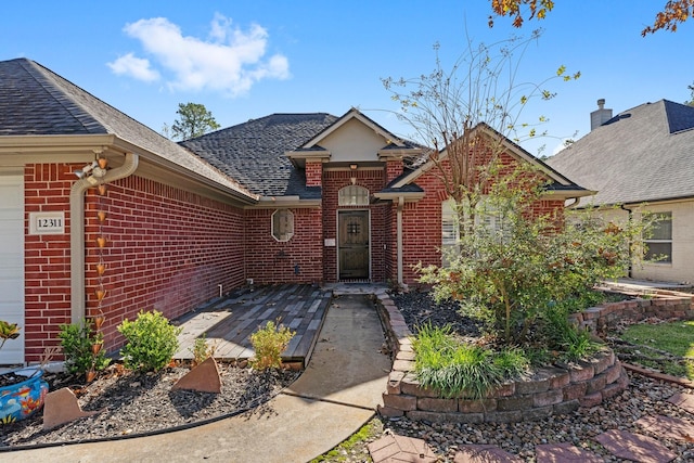 view of front facade with roof with shingles and brick siding