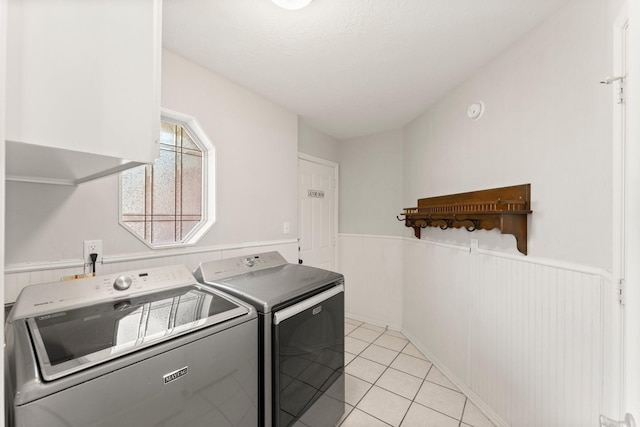 clothes washing area with light tile patterned flooring, separate washer and dryer, and wooden walls