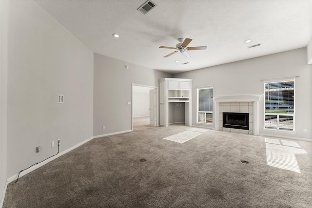 unfurnished living room with light colored carpet, ceiling fan, and a tiled fireplace