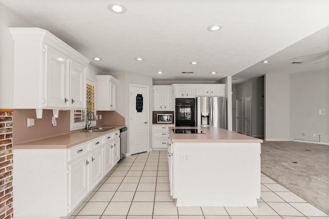 kitchen featuring white cabinetry, stainless steel appliances, a sink, and light countertops