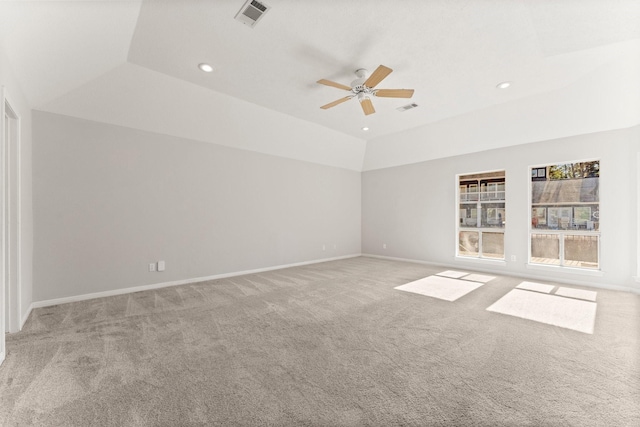 interior space with ceiling fan, vaulted ceiling, light colored carpet, and a tray ceiling