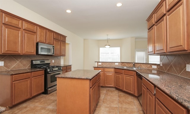 kitchen with decorative backsplash, appliances with stainless steel finishes, a kitchen island, and pendant lighting