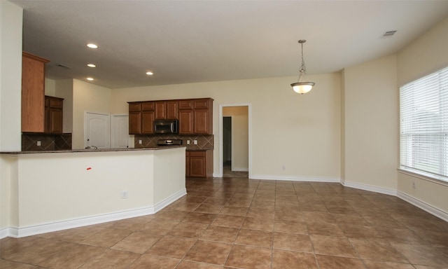 kitchen featuring pendant lighting, decorative backsplash, a healthy amount of sunlight, and kitchen peninsula