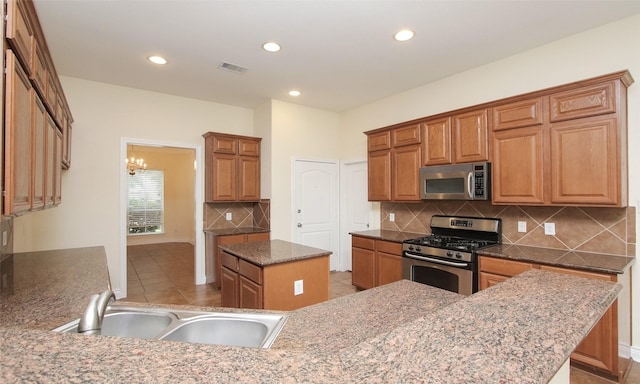 kitchen featuring a center island, sink, stainless steel appliances, backsplash, and a chandelier