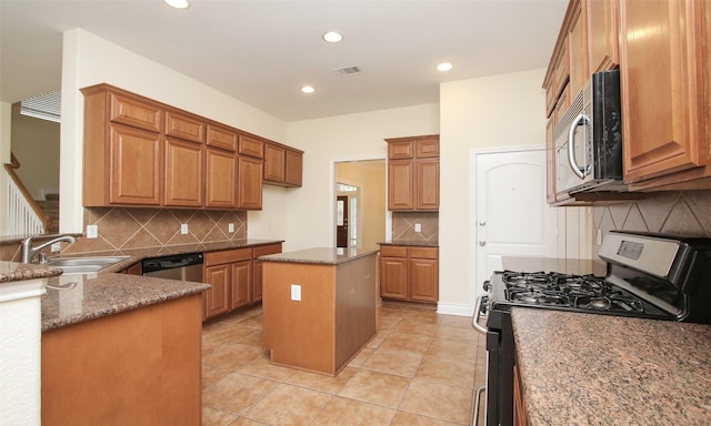 kitchen with tasteful backsplash, stainless steel appliances, sink, a kitchen island, and light tile patterned flooring