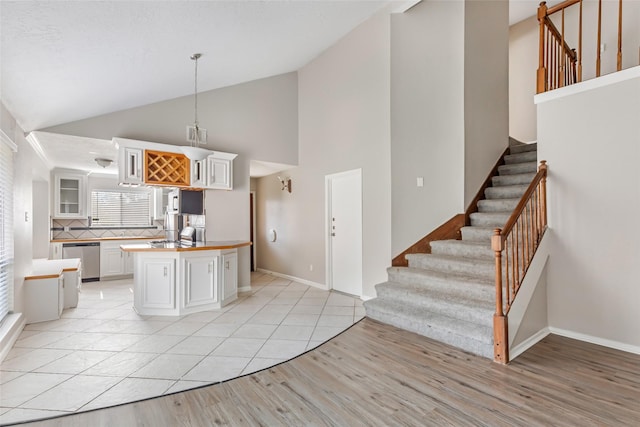 kitchen featuring white cabinetry, dishwasher, hanging light fixtures, a kitchen island, and light wood-type flooring