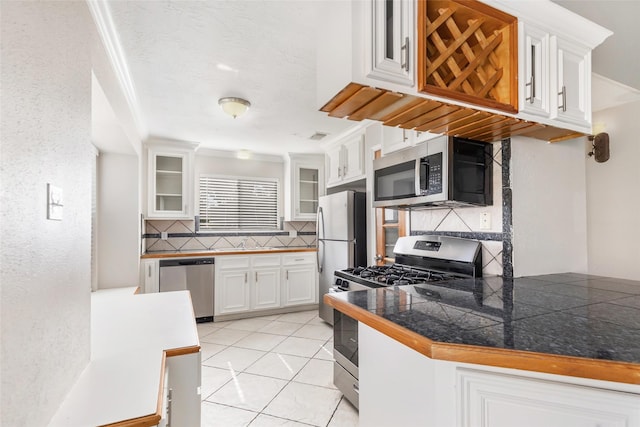 kitchen with white cabinetry, sink, backsplash, light tile patterned floors, and stainless steel appliances