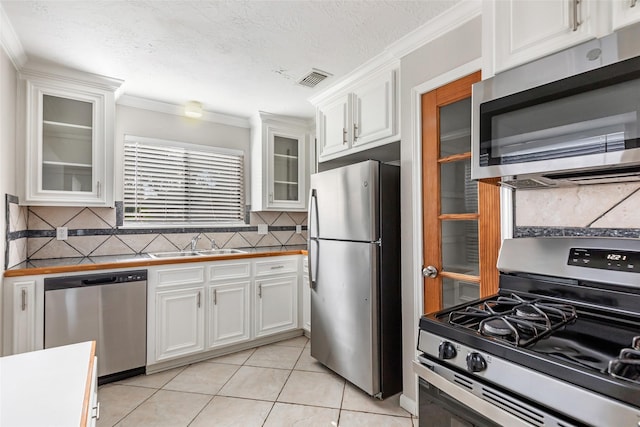 kitchen featuring tasteful backsplash, white cabinetry, appliances with stainless steel finishes, and sink