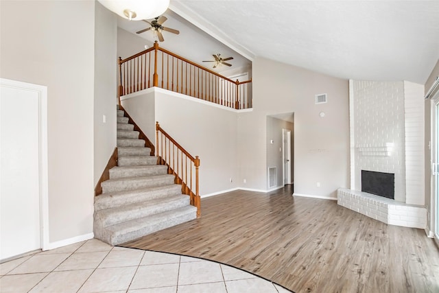 interior space featuring ceiling fan, high vaulted ceiling, a fireplace, and light hardwood / wood-style floors