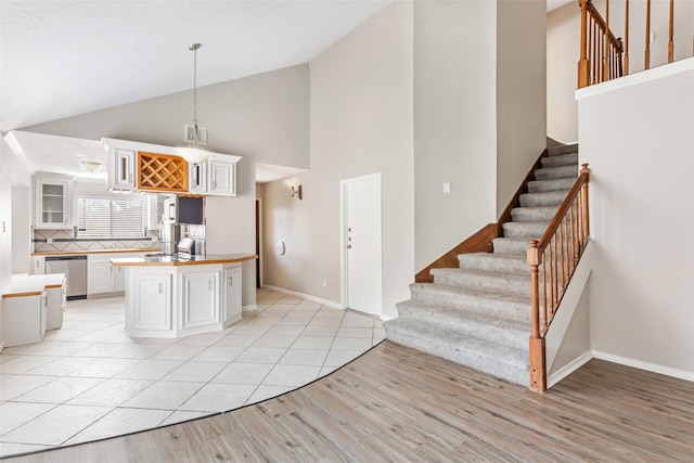 kitchen with a kitchen island, decorative light fixtures, dishwasher, white cabinets, and light hardwood / wood-style floors