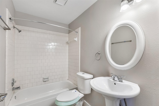 full bathroom with sink, tiled shower / bath combo, and toilet