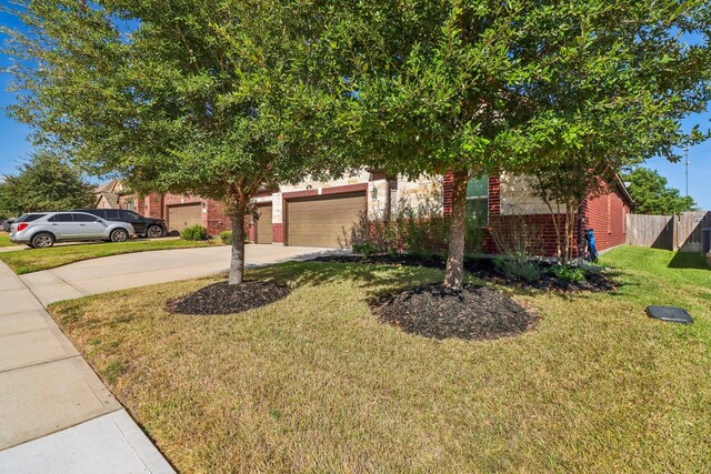 view of property hidden behind natural elements featuring a garage and a front lawn