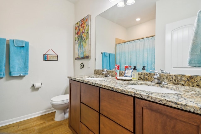 bathroom with walk in shower, hardwood / wood-style floors, vanity, and toilet