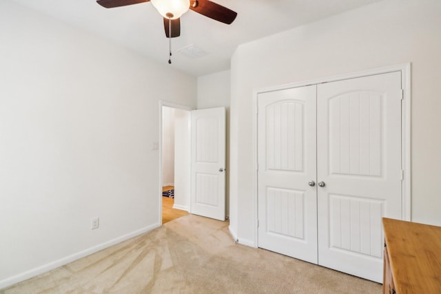 unfurnished bedroom with ceiling fan, light carpet, and a closet